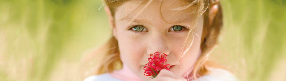 Petite fille qui respire une fleur
